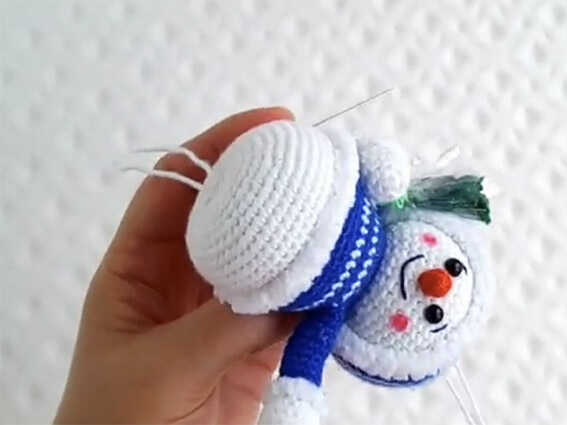 Amigurumi Assembly Guide: Close-up of sewing snowman pieces together, focusing on professional low sew finishing techniques.